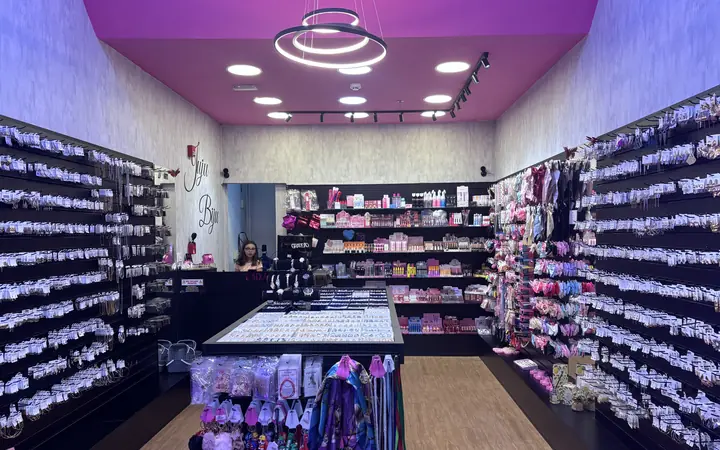 A loja por dentro, com o teto rosa, o lustre de anéis de luz e as paredes de acessórios